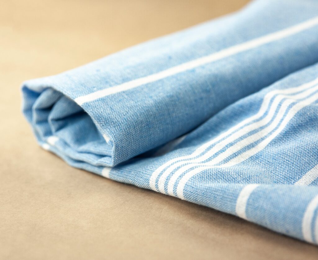 Close-up of a folded blue striped towel on beige surface for summer vibes.